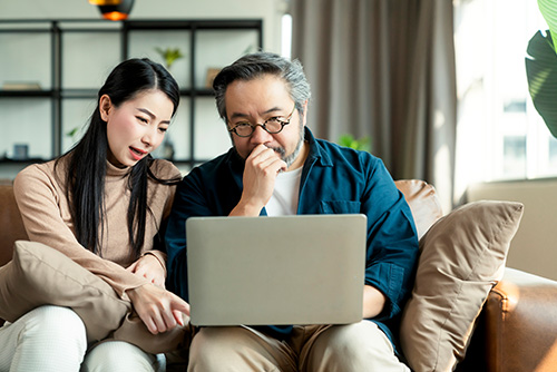 Parent co-applicant for student loan. Daughter and father looking at a laptop screen, focused on student loan application.